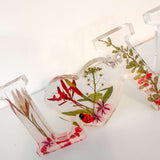 Close-up of real foraged garden greenery and red ladybug charms in resin