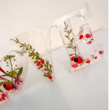 Close-up of real foraged garden greenery and red ladybug charms in resin