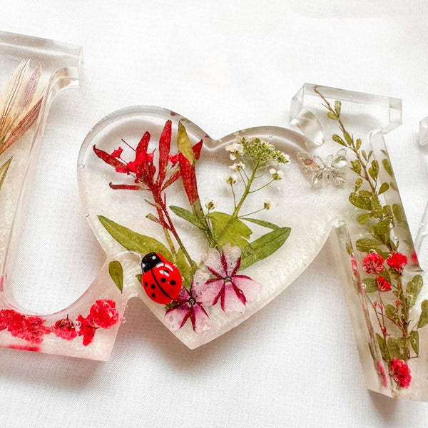 Garden Path LOVE ladybug resin word art displayed on a flat surface