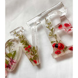 Close-up of real foraged garden greenery and red ladybug charms in resin