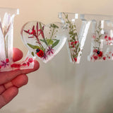 Close-up of real foraged garden greenery and red ladybug charms in resin