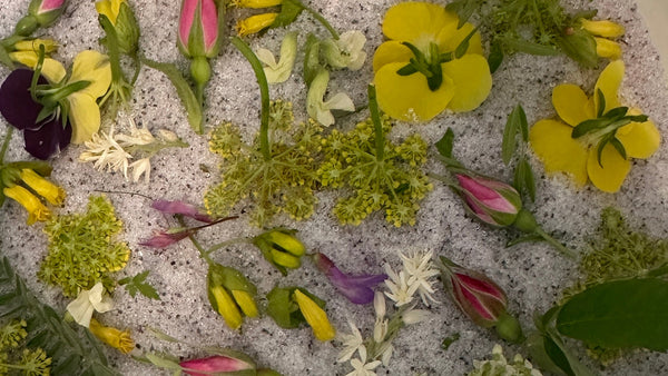Assorted flowers including yellow, green, and purple on a textured surface