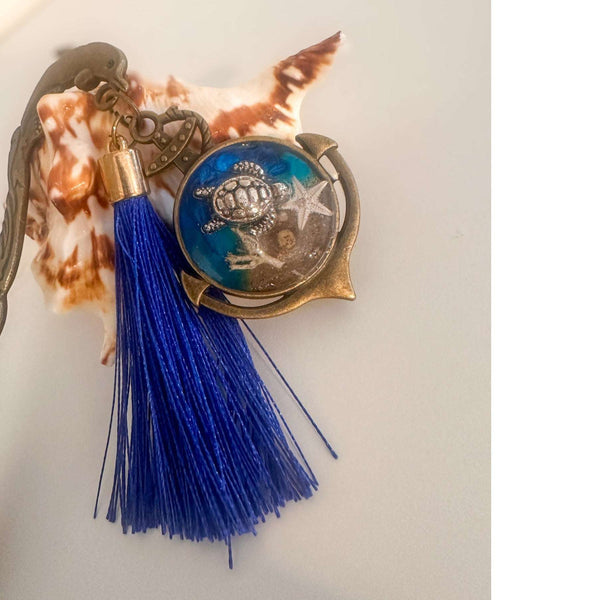 Close-up of real sand, starfish and ocean blue resin preserved inside anchor shaped bookmark charm
