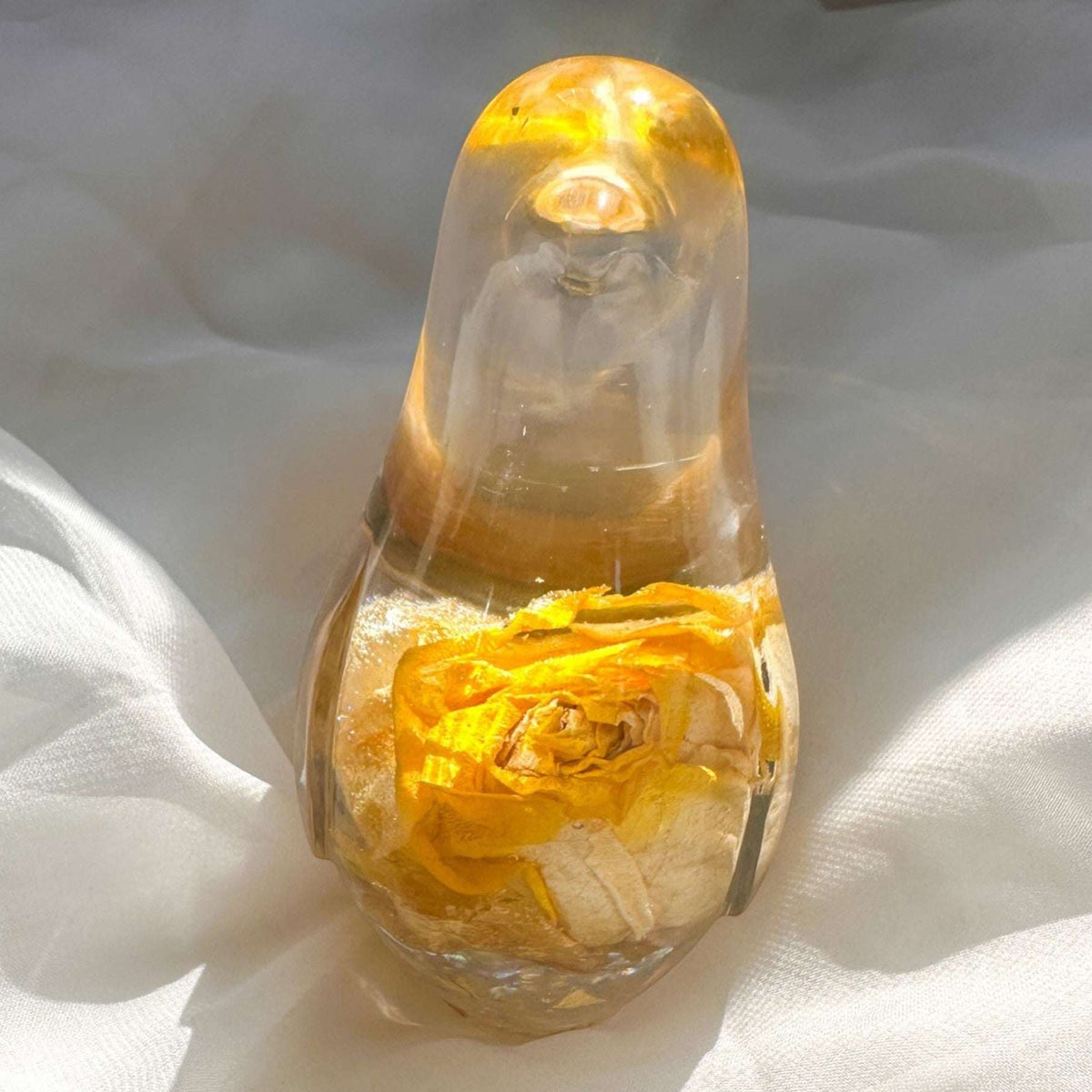 Close-up of real yellow rose bud with golden outer petals and cream inner petals preserved in clear hand-poured resin bird