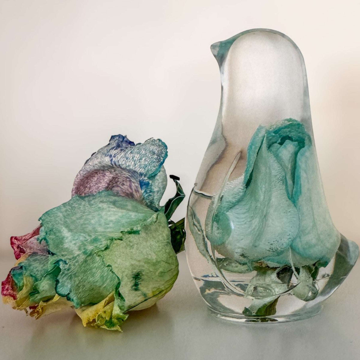  Close-up of real blue and teal rainbow rose petals and leaves preserved in clear hand-poured resin bird