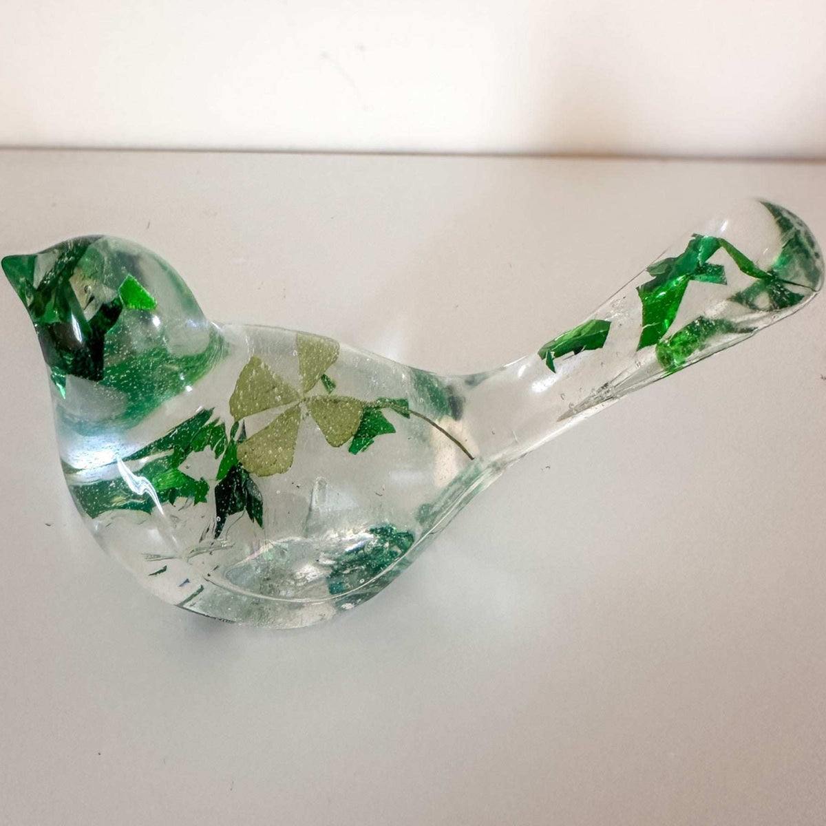 Clear resin bird figurine filled with real green four leaf clovers, vibrant green botanicals, and gold flakes,
