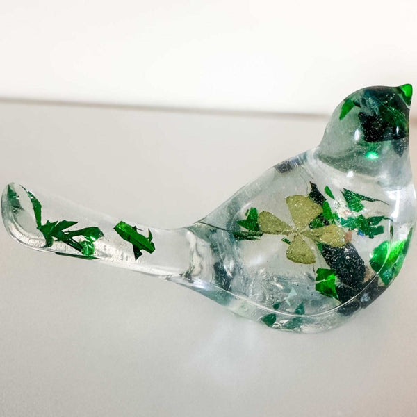 Clear resin bird figurine filled with real green four leaf clovers, vibrant green botanicals, and gold flakes,