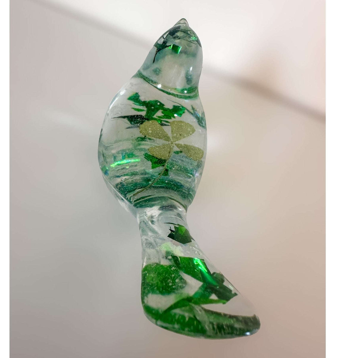 Clear resin bird figurine filled with real green four leaf clovers, vibrant green botanicals, and gold flakes,
