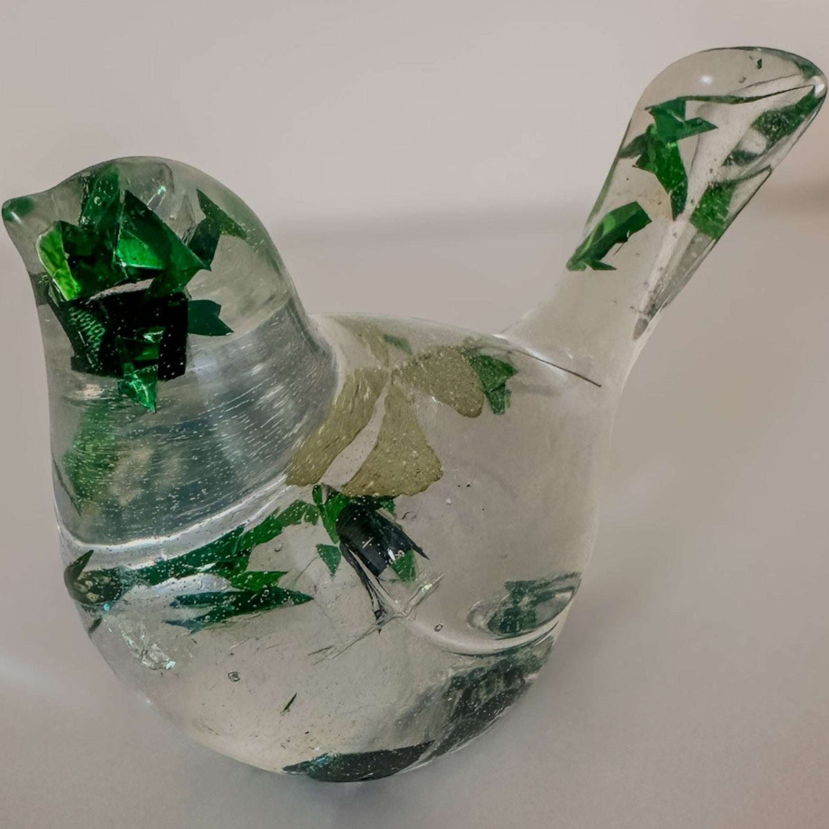 Clear resin bird figurine filled with real green four leaf clovers, vibrant green botanicals, and gold flakes,