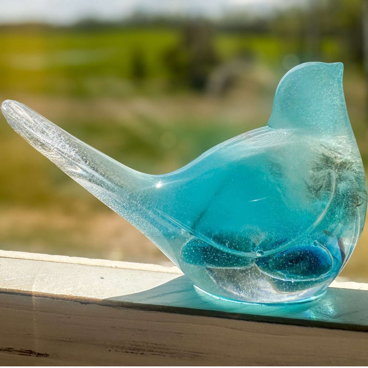 Close-up of real dandelion seeds suspended in deep teal hand-poured resin bird decor
