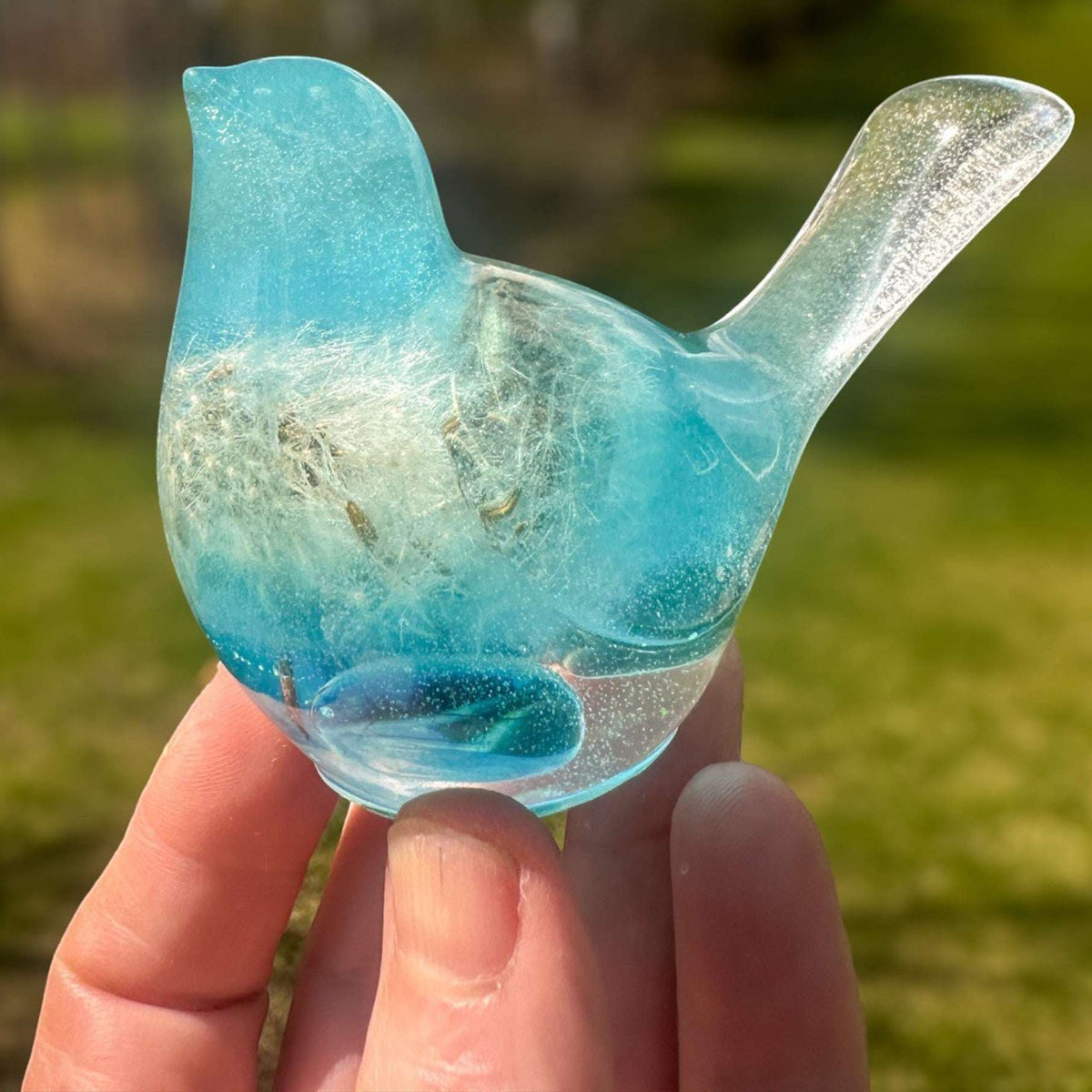 Aurora Wish Songbird teal glow resin bird decor glowing softly in a dark room held in hand