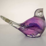 Close-up of soft purple and pink rainbow rose petals suspended in clear hand-poured resin bird figurine