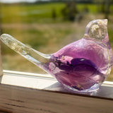 Close-up of soft purple and pink rainbow rose petals suspended in clear hand-poured resin bird figurine