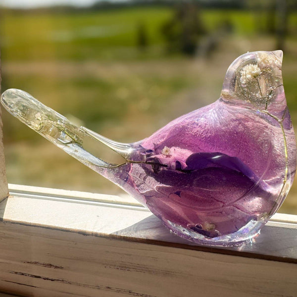 Close-up of soft purple and pink rainbow rose petals suspended in clear hand-poured resin bird figurine