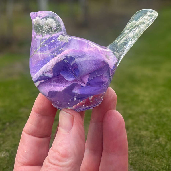 Close-up of soft purple and pink rainbow rose petals suspended in clear hand-poured resin bird figurine