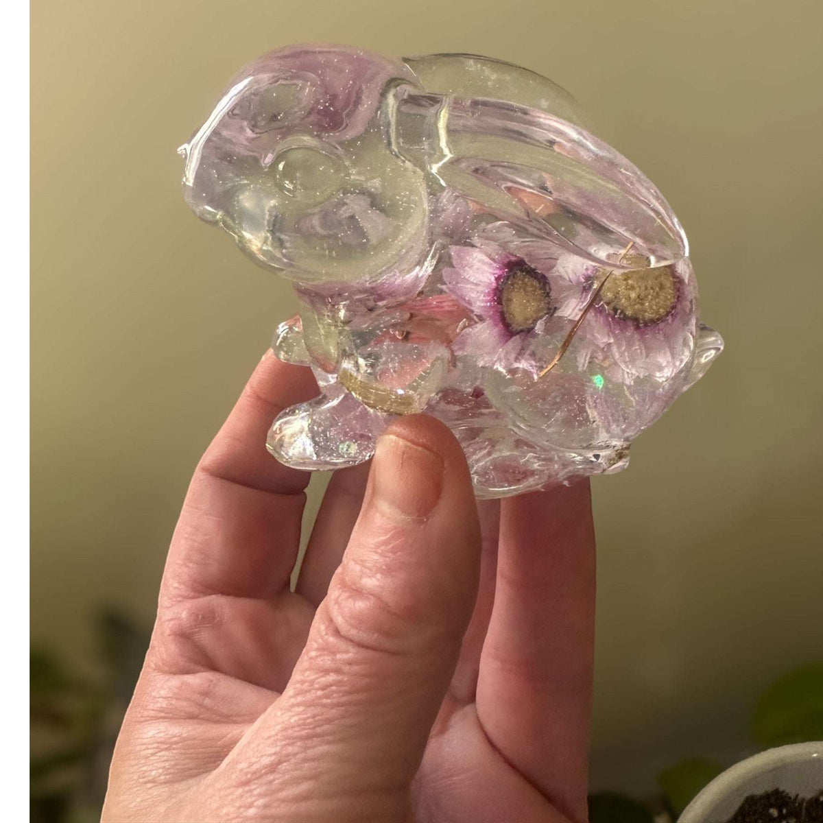 Close-up of real pink spring blooms suspended inside clear hand-poured resin bunny figurine