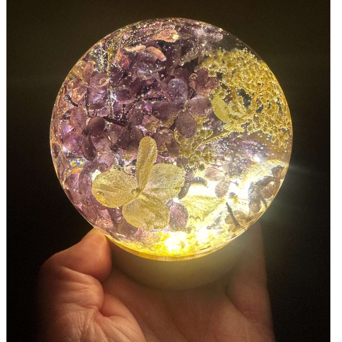 Handcrafted purple lilac resin sphere with real lilac and white hydrangea blooms on glowing LED base