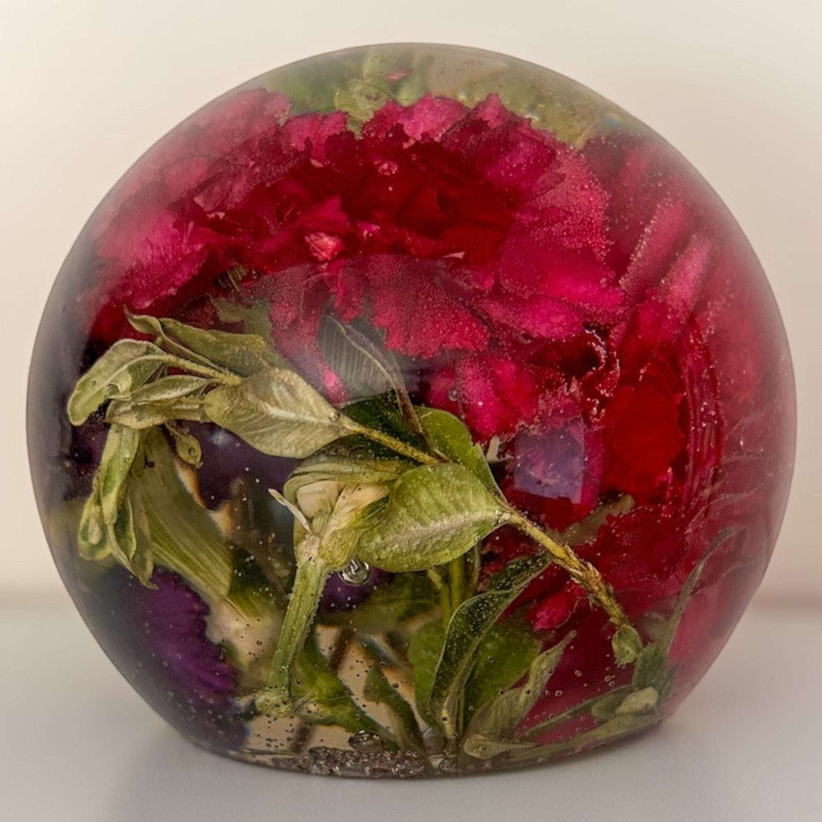 Handcrafted floral resin sphere with preserved dark pink and purple carnations and green botanicals on LED light base