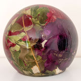 Handcrafted floral resin sphere with real dark pink and purple carnations and LED base glowing as a decorative garden nightlight