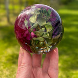 Handcrafted floral resin sphere with preserved pink and purple carnations and green botanicals on LED light base