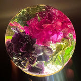 Handcrafted floral resin sphere with dark pink and purple carnations and LED base glowing as indoor garden decor