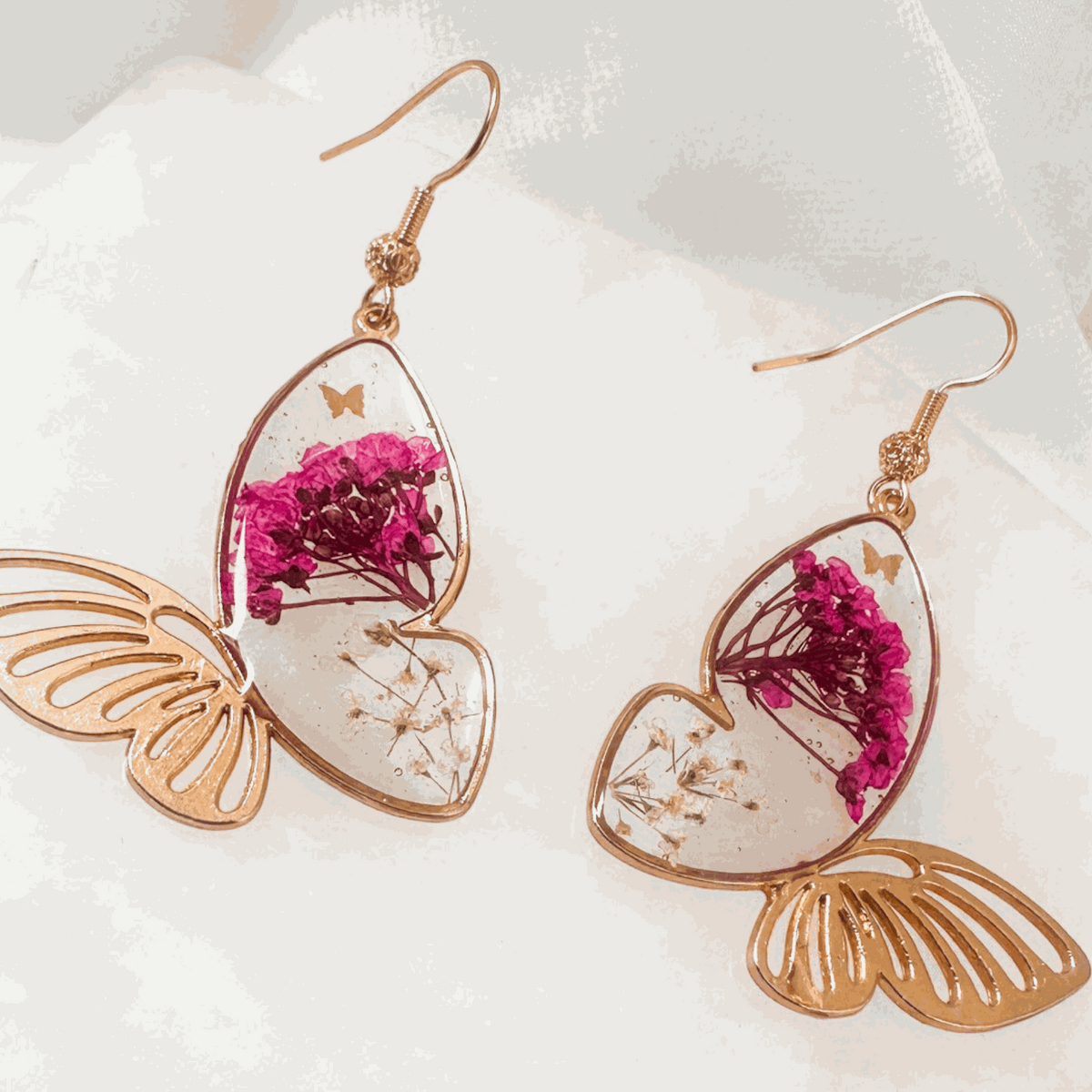 Rose gold Garden Wing Earrings with deep pink and white pressed flower butterfly wings encased in resin, lightweight and hypoallergenic