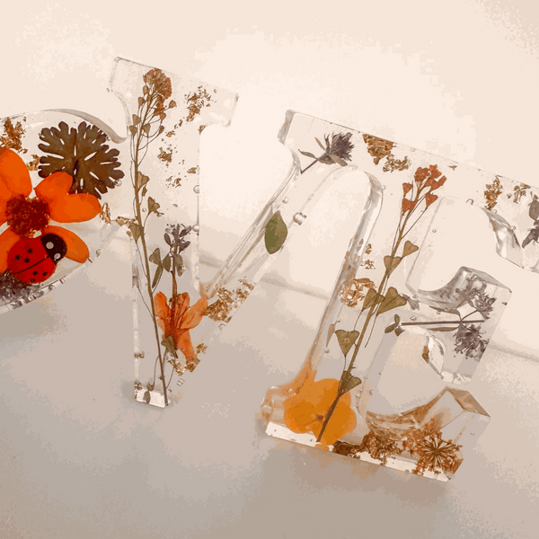 Pressed flower resin decor spelling LOVE with real pressed wildflowers and tiny ladybug in clear resin letters