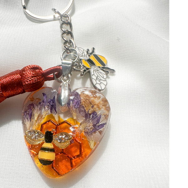 Honeybee Heart Bag Charm with rhinestone bee, golden honeycomb, pressed purple flowers, enamel bee charm, and copper tassel on silver keychain ring
