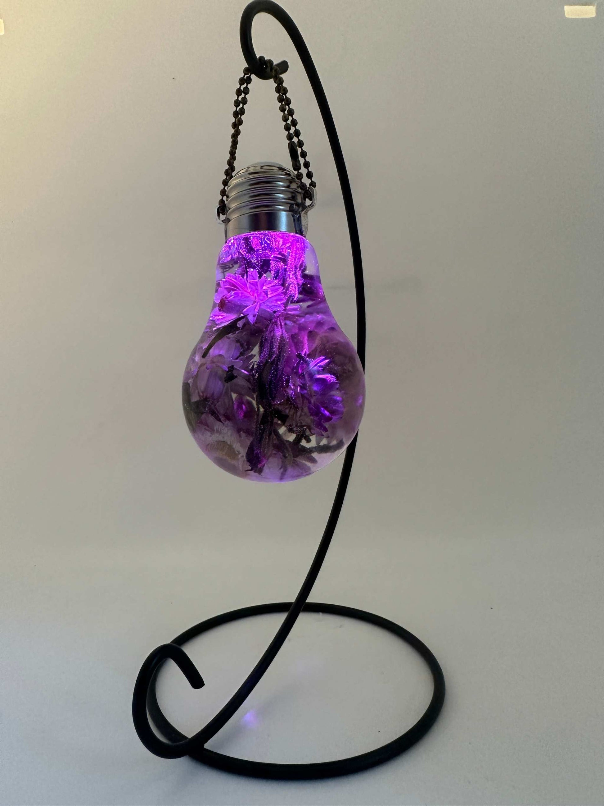 A "lightbulb" created with Epoxy resin and dried straw flowers. Comes with a USB charger. Light bulb has a variety of colours that it will light up with. A nice home decor piece