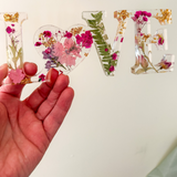 Fuchsia Garden LOVE resin word art with pressed pink and fuchsia flowers, fern fronds, and gold leaf flakes