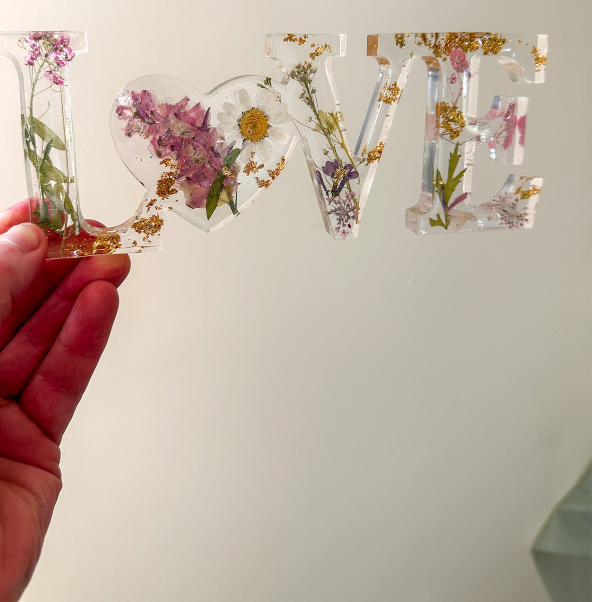 Daisy resin word artfeaturing real pressed white daisy and blush blooms with gold leaf flakes and heart-shaped O design