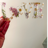 Daisy resin word artfeaturing real pressed white daisy and blush blooms with gold leaf flakes and heart-shaped O design