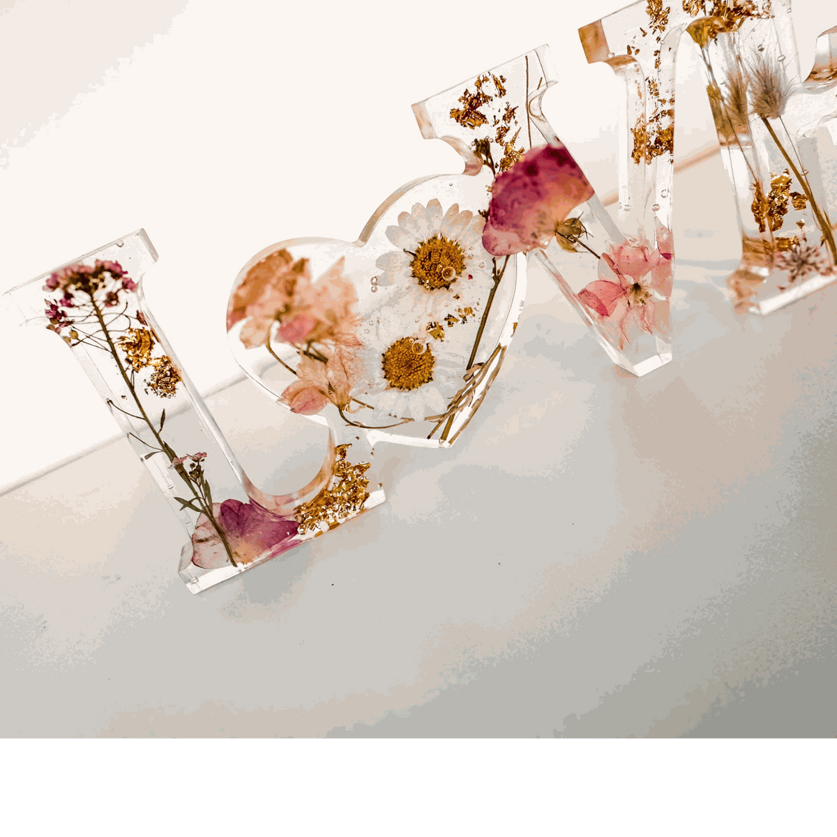 Whispering Meadow LOVE resin word art with white daisies, pink and purple wildflowers, bunny tail, and gold leaf flakes