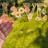Whispering Meadow LOVE resin word art with white daisies, pink and purple wildflowers, gold leaf flakes, and a bunny tail accent