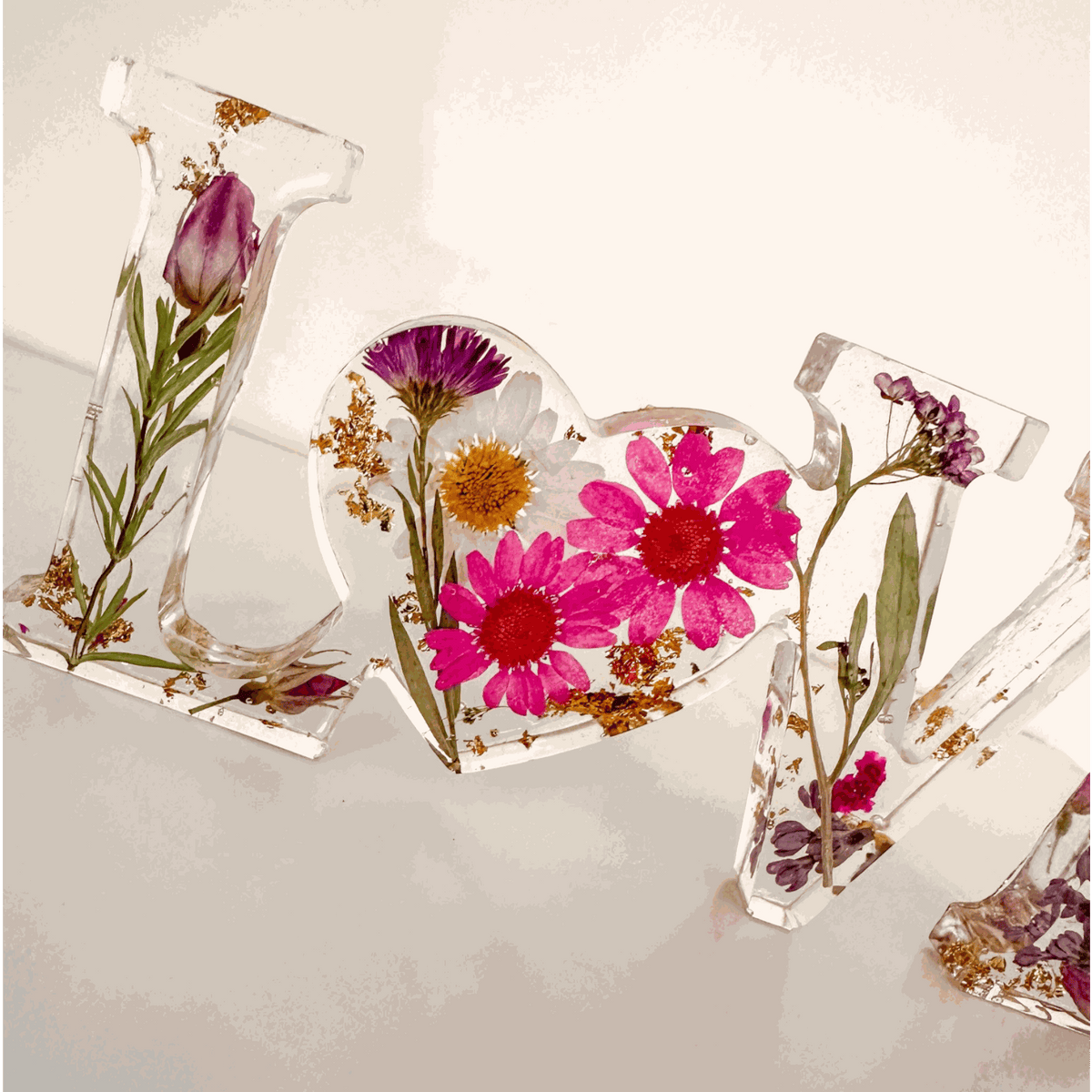 Wildflower resin word art with pink daisies, white daisy, purple wildflowers, rose buds, and gold leaf flakes in LOVE letters