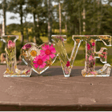 Wildflower meadow LOVE word art with pink daisies, purple wildflowers, rose buds, and gold leaf in clear resin letters