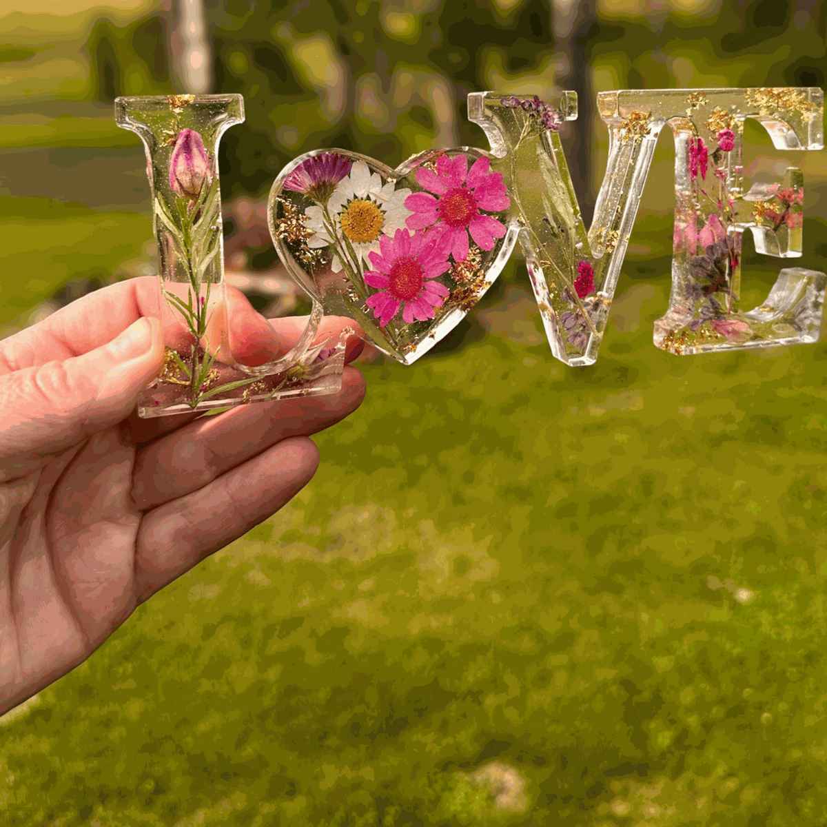 Wildflower resin word art with pink daisies, purple wildflowers, rose buds, and gold leaf flakes spelling LOVE