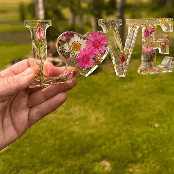 Wildflower resin word art with pink daisies, purple wildflowers, rose buds, and gold leaf flakes spelling LOVE