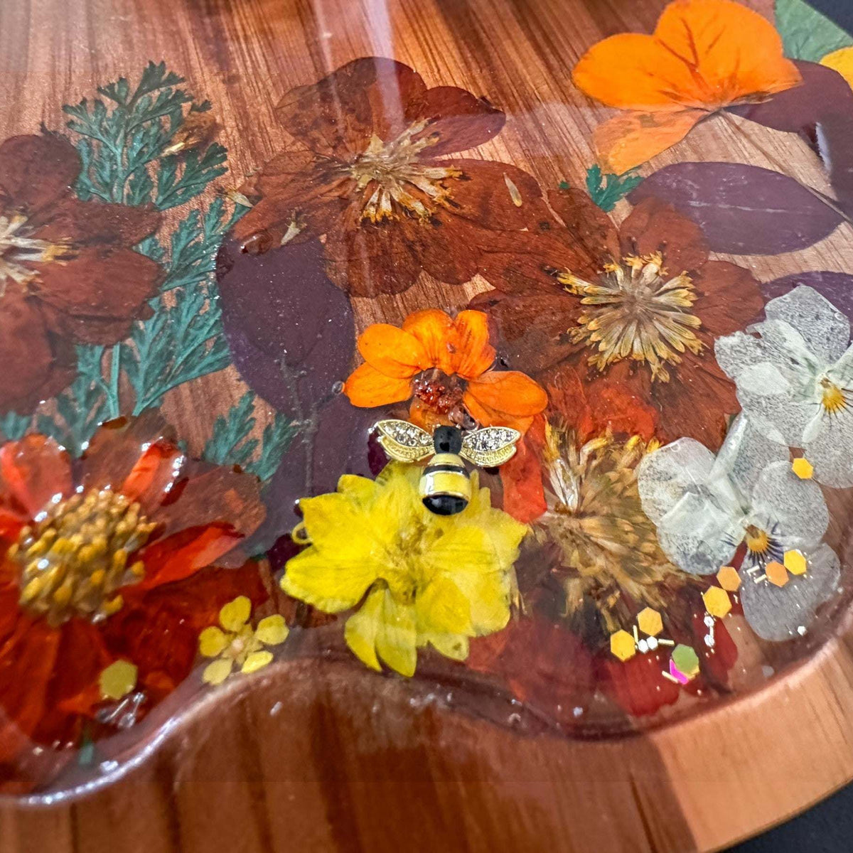 Handcrafted wooden pumpkin tray with real pressed sunflower, dried botanicals, bee charm, and gold glitter, perfect for fall decor.
