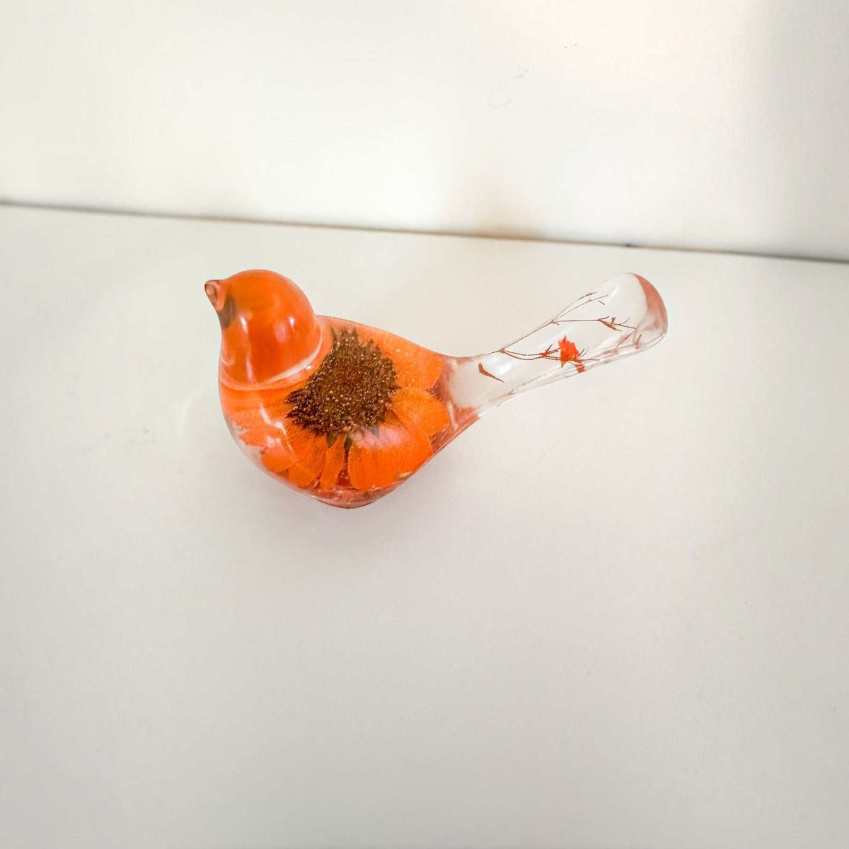 Orange sunflower resin bird decor with a bright orange flower body and clear tail featuring small floral accents and copper leaf base.
