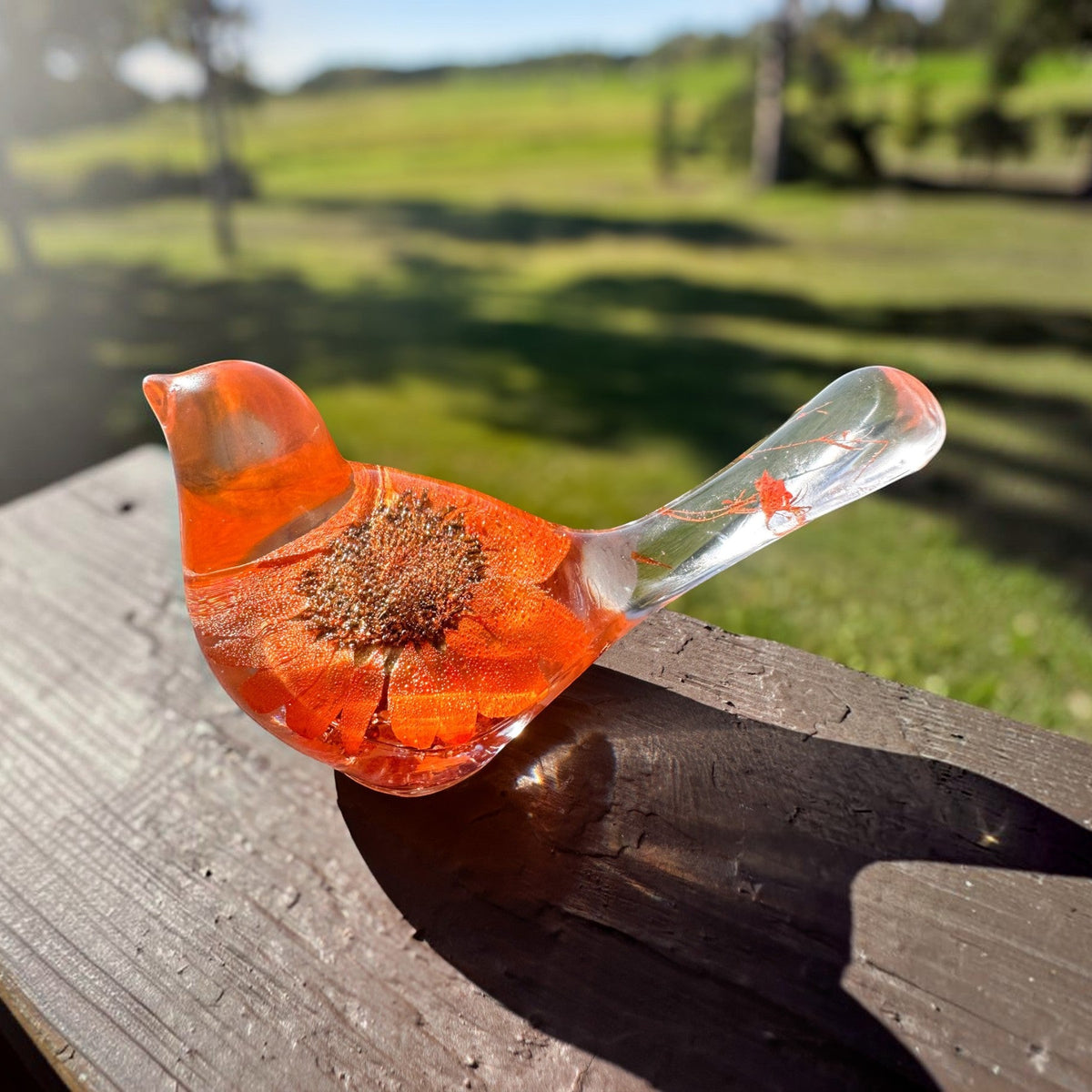 Orange sunflower resin bird decor with bright orange petals and clear tail featuring small flower accents and copper leaf base