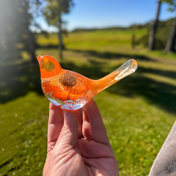 Resin bird decor featuring a bright orange sunflower encased in clear resin with copper leaf accents and floral details in the tail.