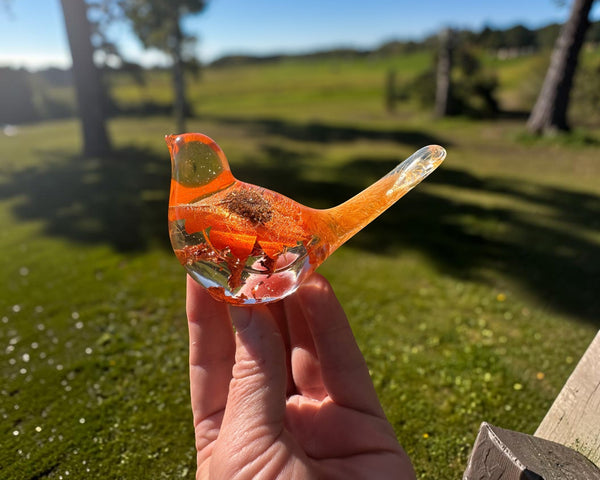 Orange sunflower resin bird decor with clear body, bright orange flower petals, and copper leaf accents at the base.