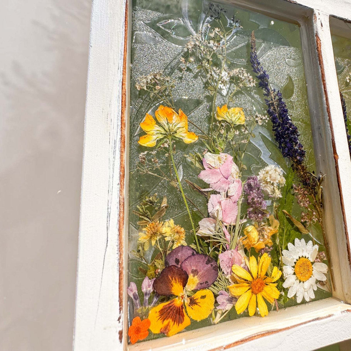 Pressed Flower Window Frame wall art with real dried yellow, purple, white, and orange wildflowers set in clear resin within a distressed white wood frame