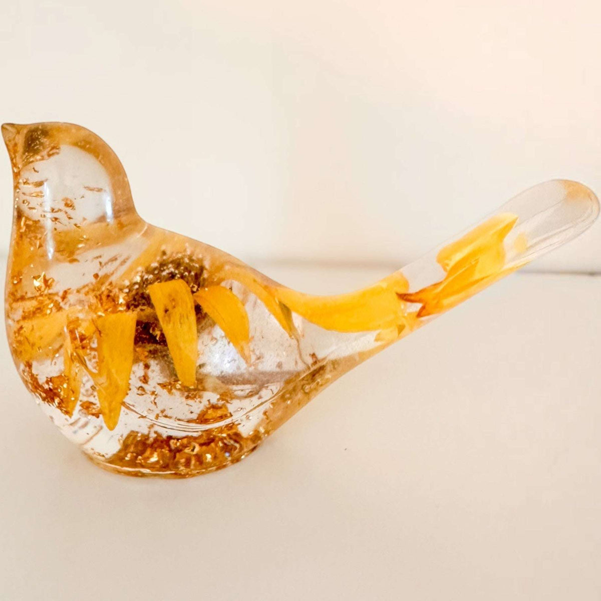 Sunflower resin bird decor with clear body, embedded real yellow petals, gold flecks, and a long tail detail.