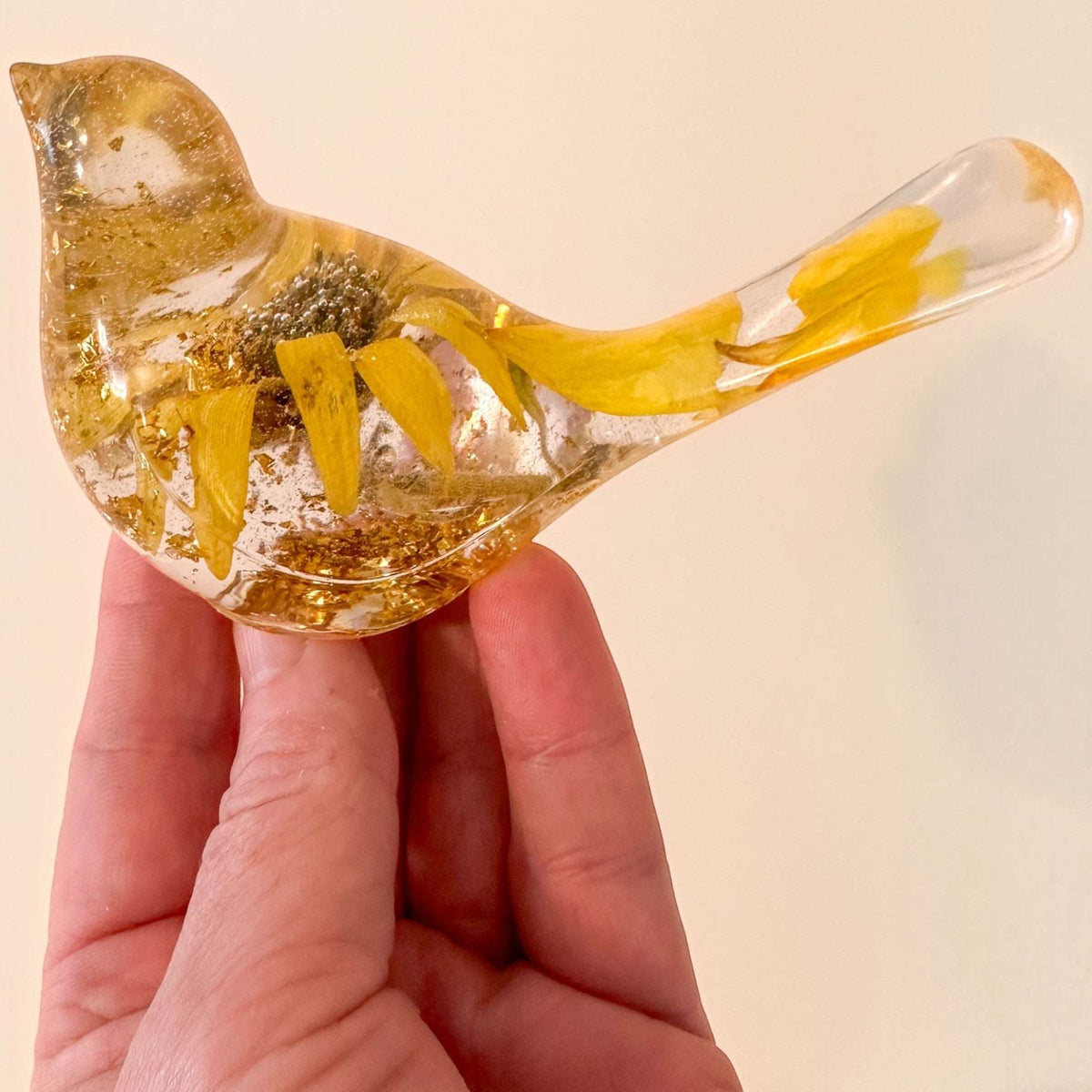Sunflower resin bird decor with clear hand-poured resin, real dried yellow sunflower petals, and gold leaf accents inside a small bird shape.