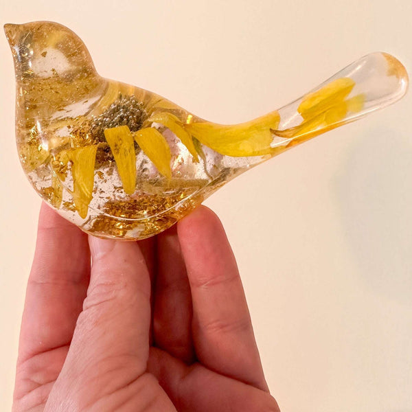 Sunflower resin bird decor with clear hand-poured resin, real dried yellow sunflower petals, and gold leaf accents inside a small bird shape.