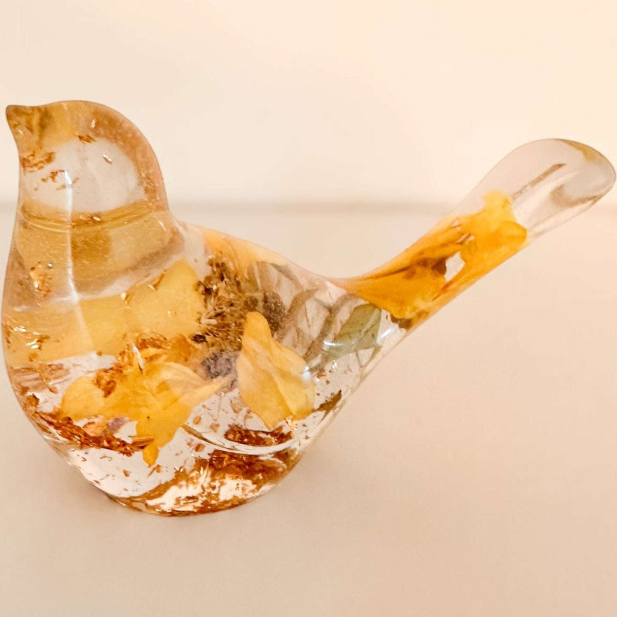 Sunflower resin bird decor with clear glossy finish, embedded real dried yellow sunflower petals, and gold leaf accents in tail and body.