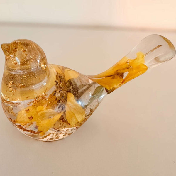 Sunflower resin bird decor in clear resin with preserved yellow sunflower petals and gold leaf accents inside a small bird shape.