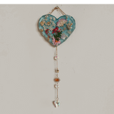 Glow in the dark heart suncatcher handcrafted in blue resin with pressed wildflowers, gold leaf, and decorative gold chain with crystal drops.